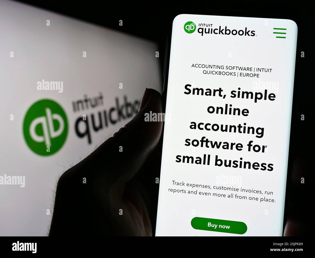 Stuttgart, Germany, 07-09-2023: Person holding cellphone with webpage of accounting software QuickBooks on screen in front of logo. Focus on center Stock Photo