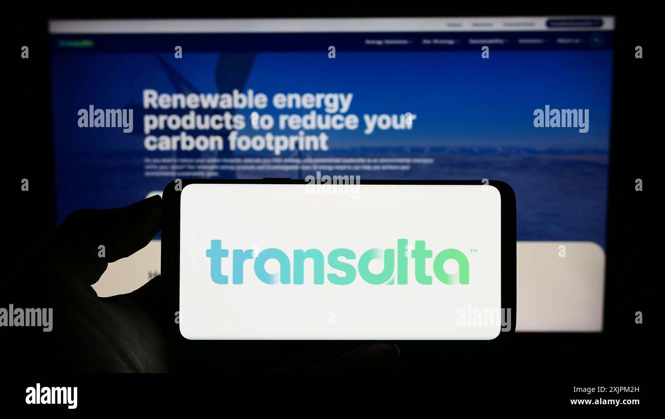 Stuttgart, Germany, 07-21-2023: Person holding cellphone with logo of Canadian energy company TransAlta Corporation on screen in front of webpage. Stock Photo