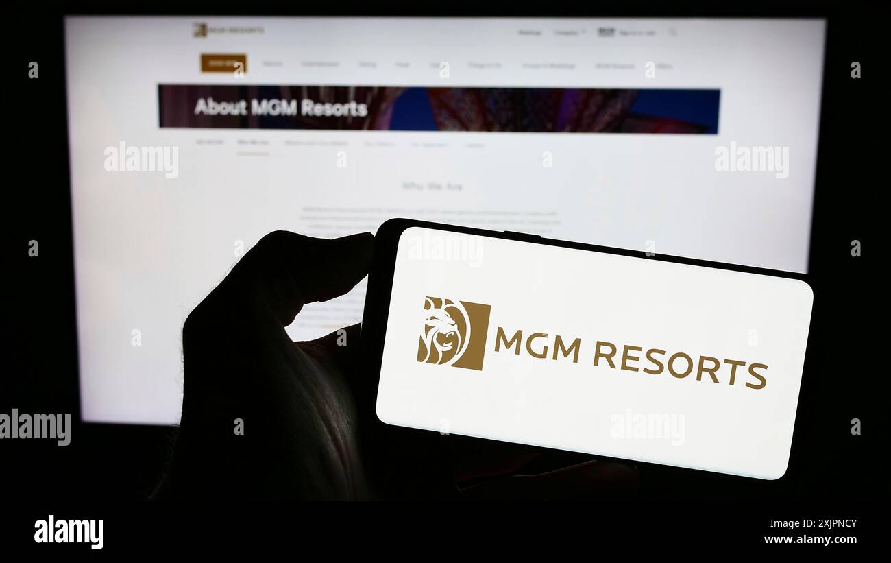 Stuttgart, Germany, 08-04-2023: Person holding smartphone with logo of hospitality company MGM Resorts International on screen in front of website. Stock Photo