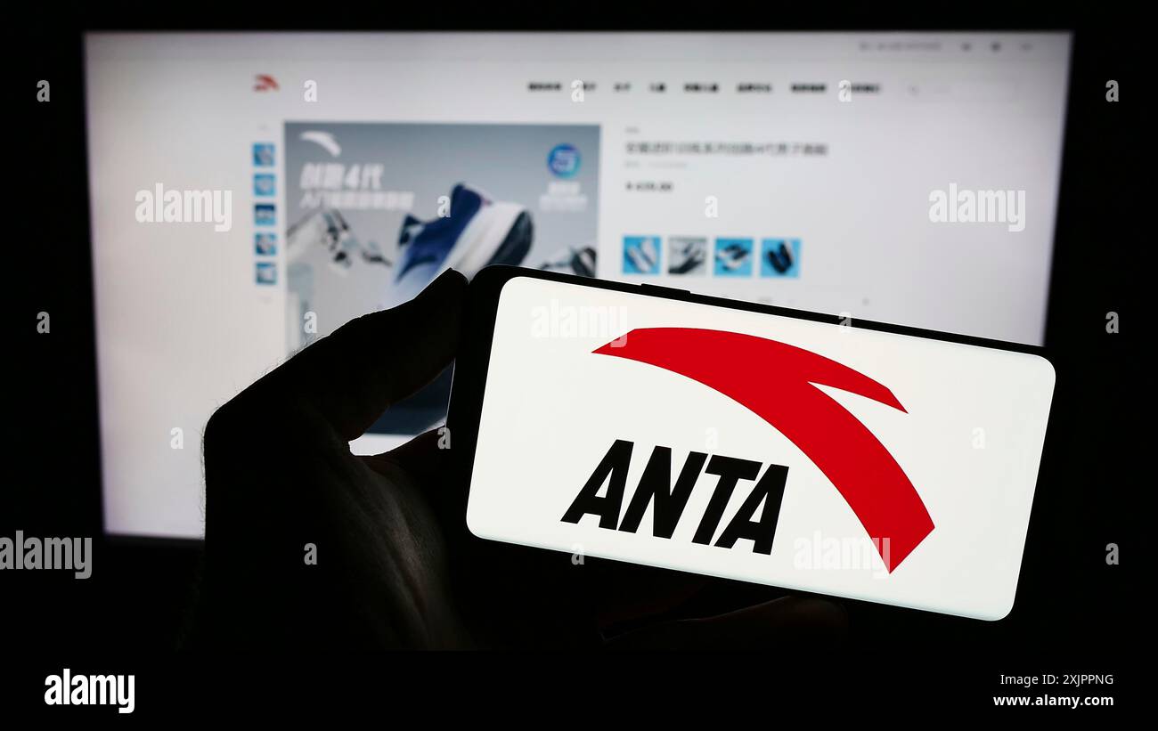 Stuttgart, Germany, 08-15-2023: Person holding smartphone with logo of Chinese company Anta Sports Products Limited on screen in front of website. Stock Photo