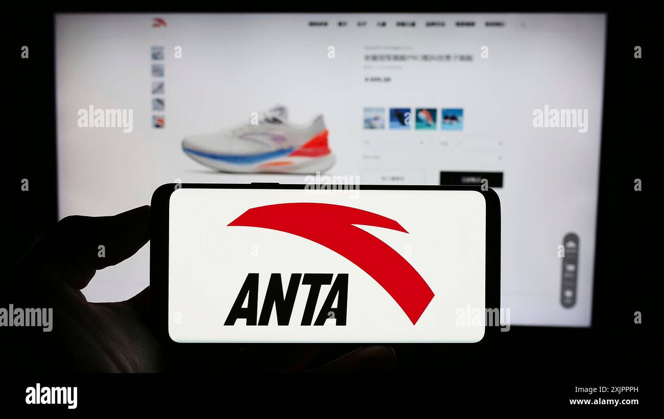 Stuttgart, Germany, 08-15-2023: Person holding cellphone with logo of Chinese company Anta Sports Products Limited on screen in front of webpage. Stock Photo