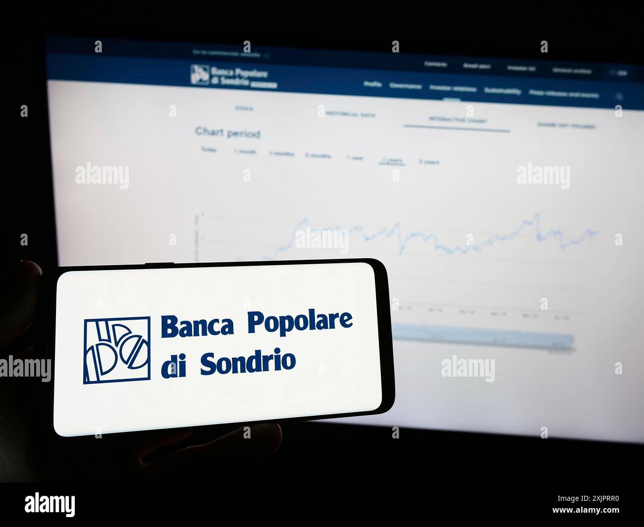 Stuttgart, Germany, 08-30-2023: Person holding mobile phone with logo of Banca Popolare di Sondrio SCpA (BPSO) on screen in front of business web Stock Photo