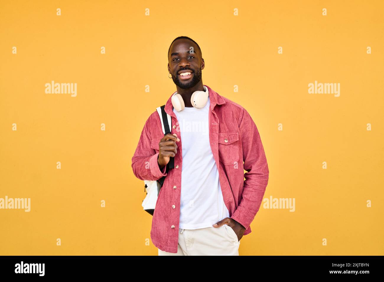 Happy young African man student standing isolated on yellow background. Stock Photo