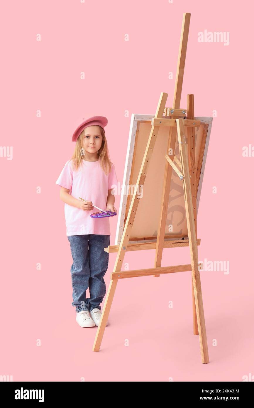 Cute little girl in beret with brush, paint palette and easel on pink ...