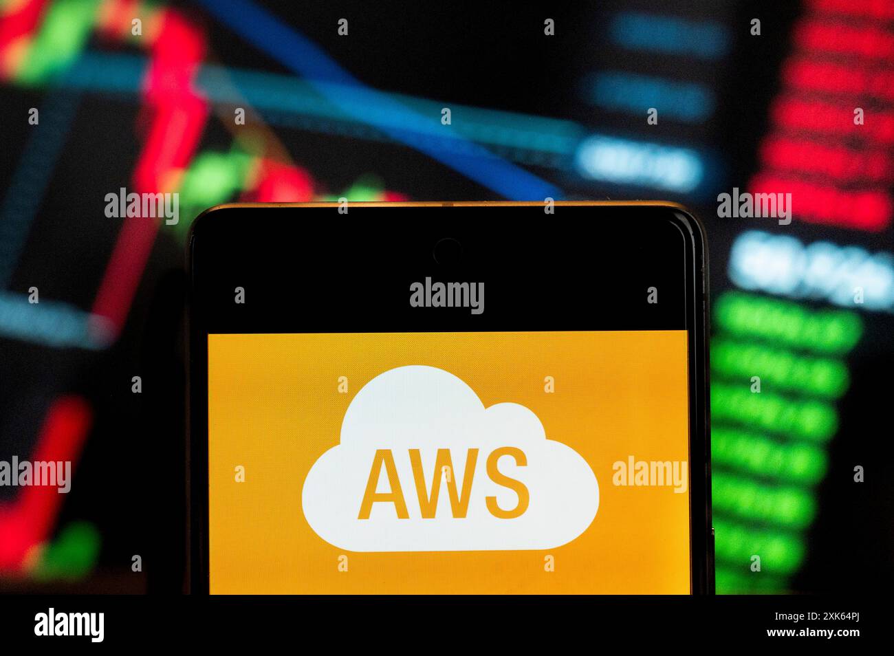 In this photo illustration, the American on-demand cloud computing platform owned by Amazon, Amazon Web Services (AWS), logo seen displayed on a smartphone with an economic stock exchange index graph in the background. Stock Photo