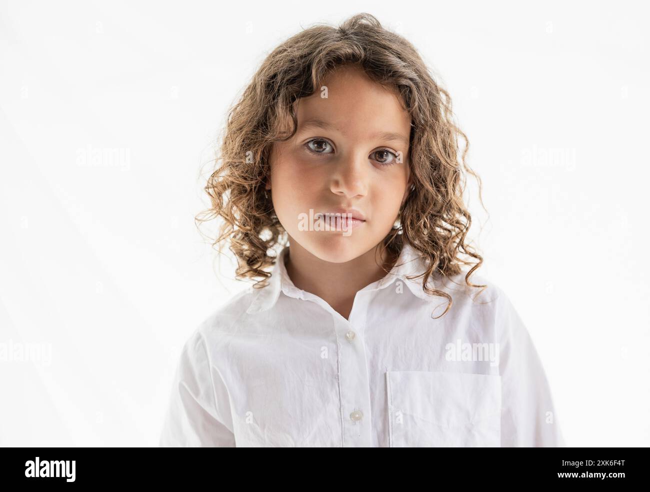Expressive close-up portrait of a young girl with curly hair wearing a ...