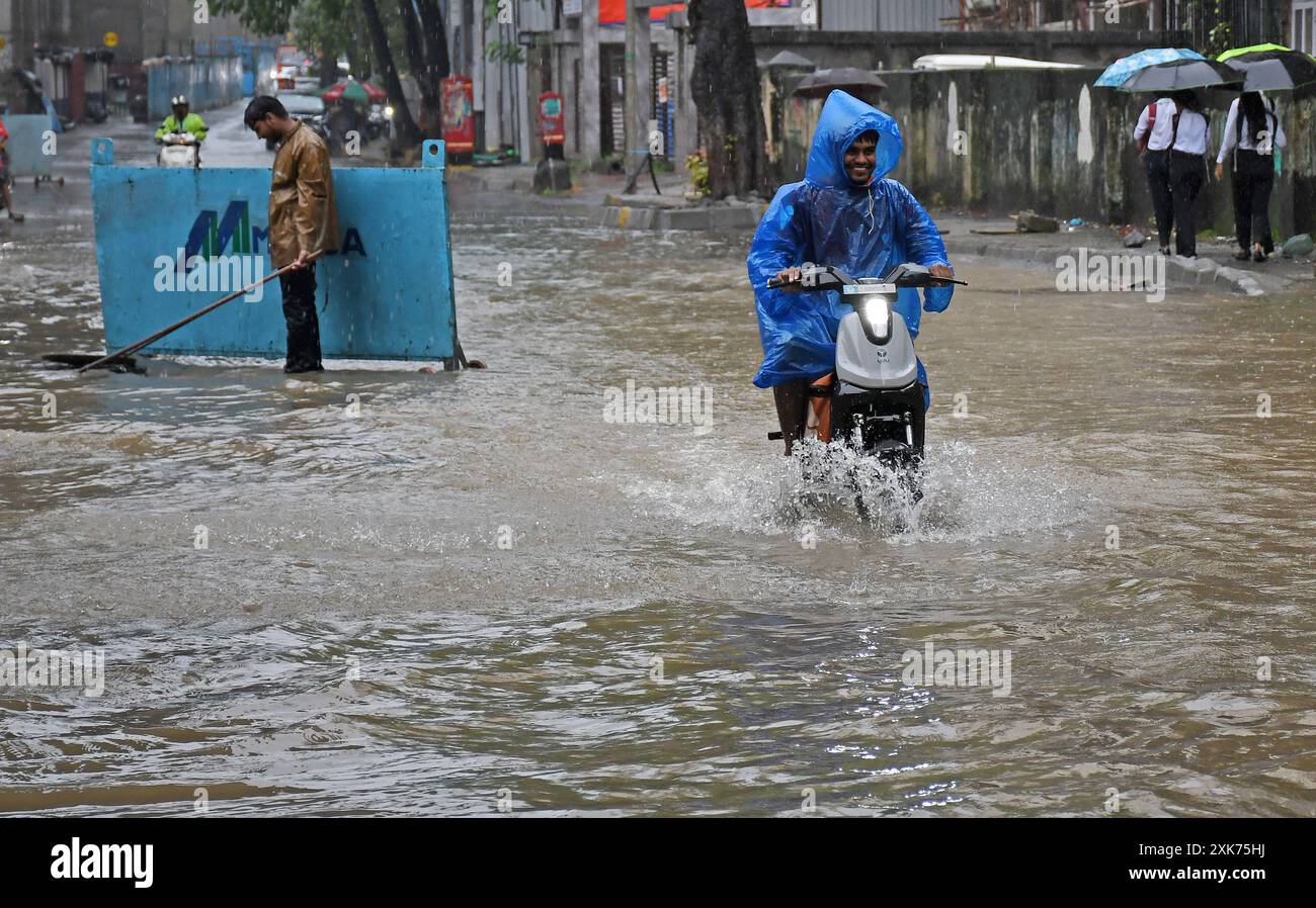 Mumbai, India. 21st July, 2024. A man wearing a raincoat rides a electric bike on a street flooded with water due to heavy rain in Mumbai. Citizens are advised to stay indoors and venture out only in case of an emergency as heavy rains lashed throughout the day which lead to flooding in many low lying areas in the city. (Photo by Ashish Vaishnav/SOPA Images/Sipa USA) Credit: Sipa USA/Alamy Live News Stock Photo