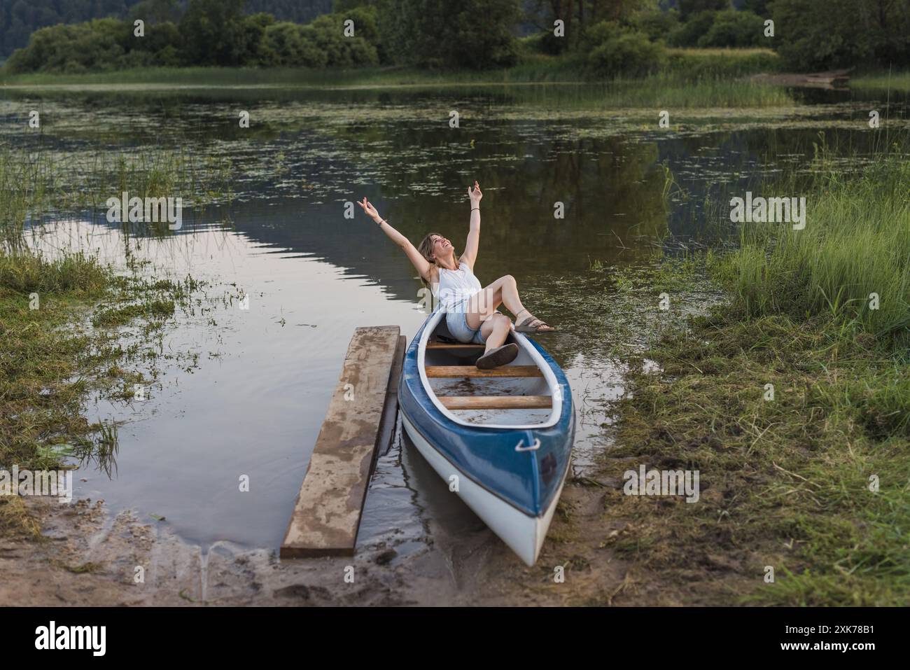 Portrait of a young woman relaxing in a canoe on a lake in nature Stock Photo