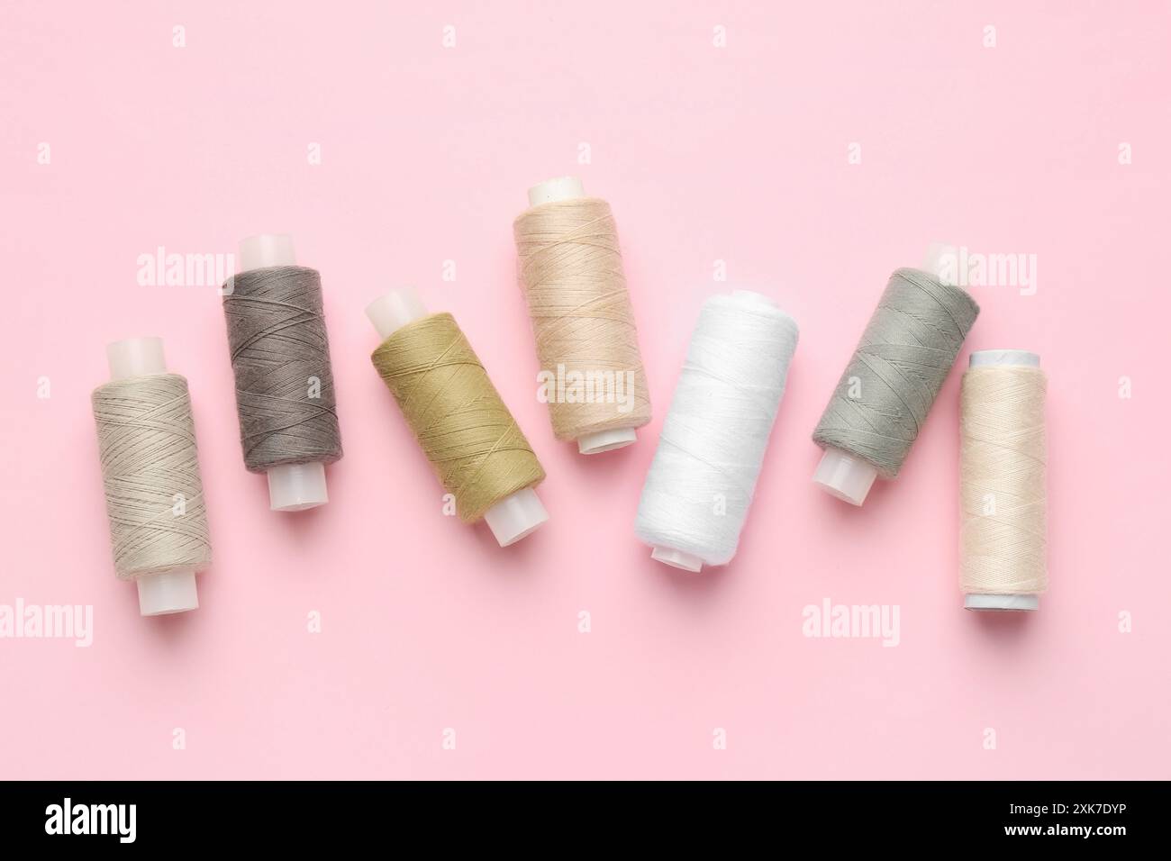 Flat lay composition with spools of sewing threads on pink background Stock Photo