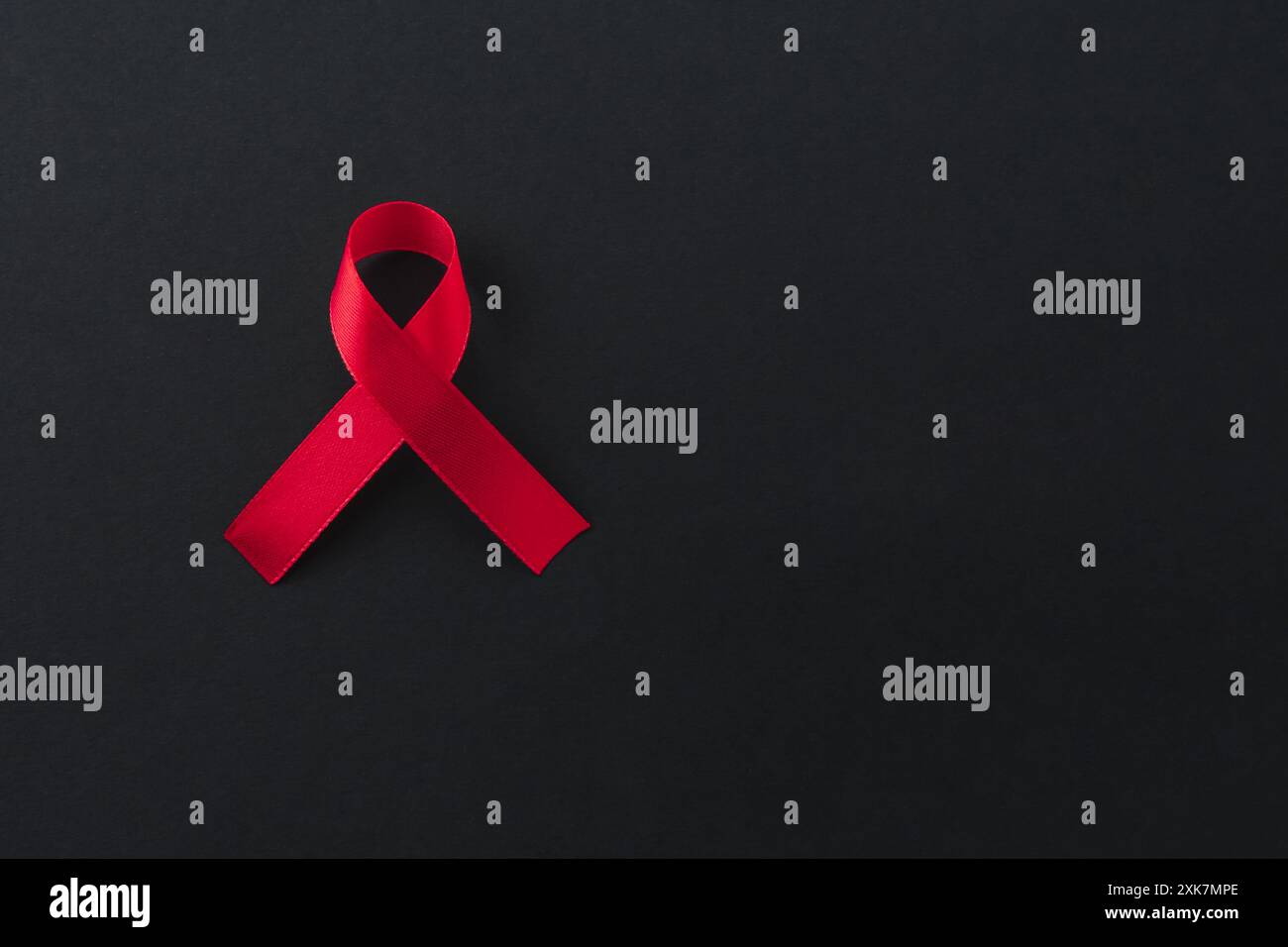 Red awareness ribbon on black background, top view. Space for text ...
