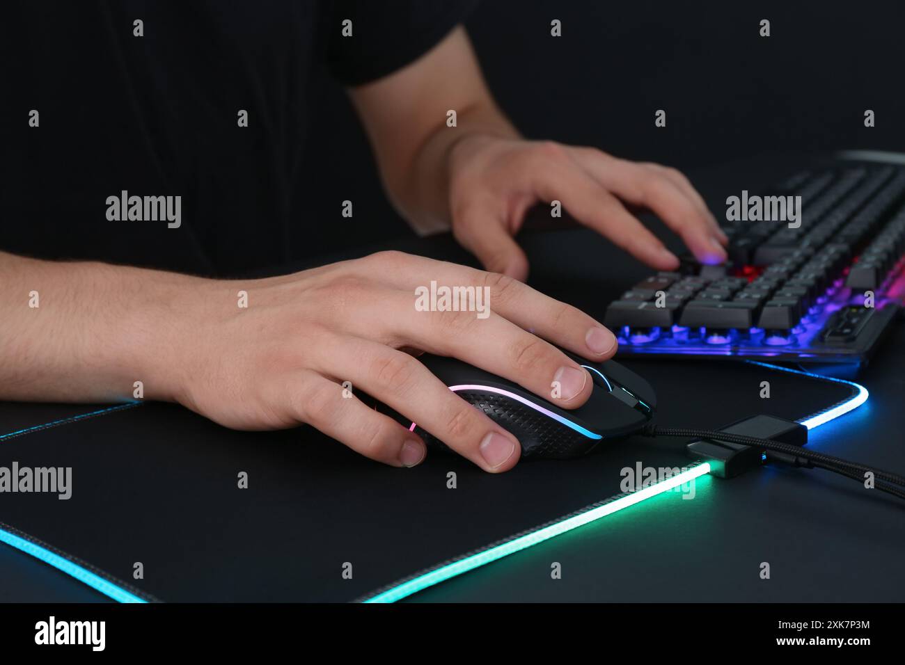 Gamer using modern wired computer mouse at black table, closeup Stock Photo