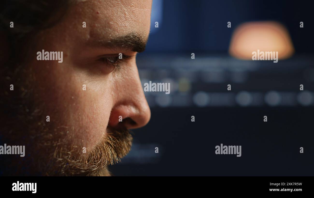 Developer in home office concentrating hard while doing coding on computer, extreme close up shot. Focus on IT admin paying close attention to screen while writing lines of code, camera A Stock Photo