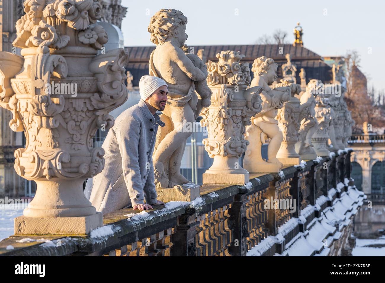 Happy young Asian traveler in a light coat traveling around the world. Seeing the sights of the new place. Stands among the monuments. Dresden, German Stock Photo