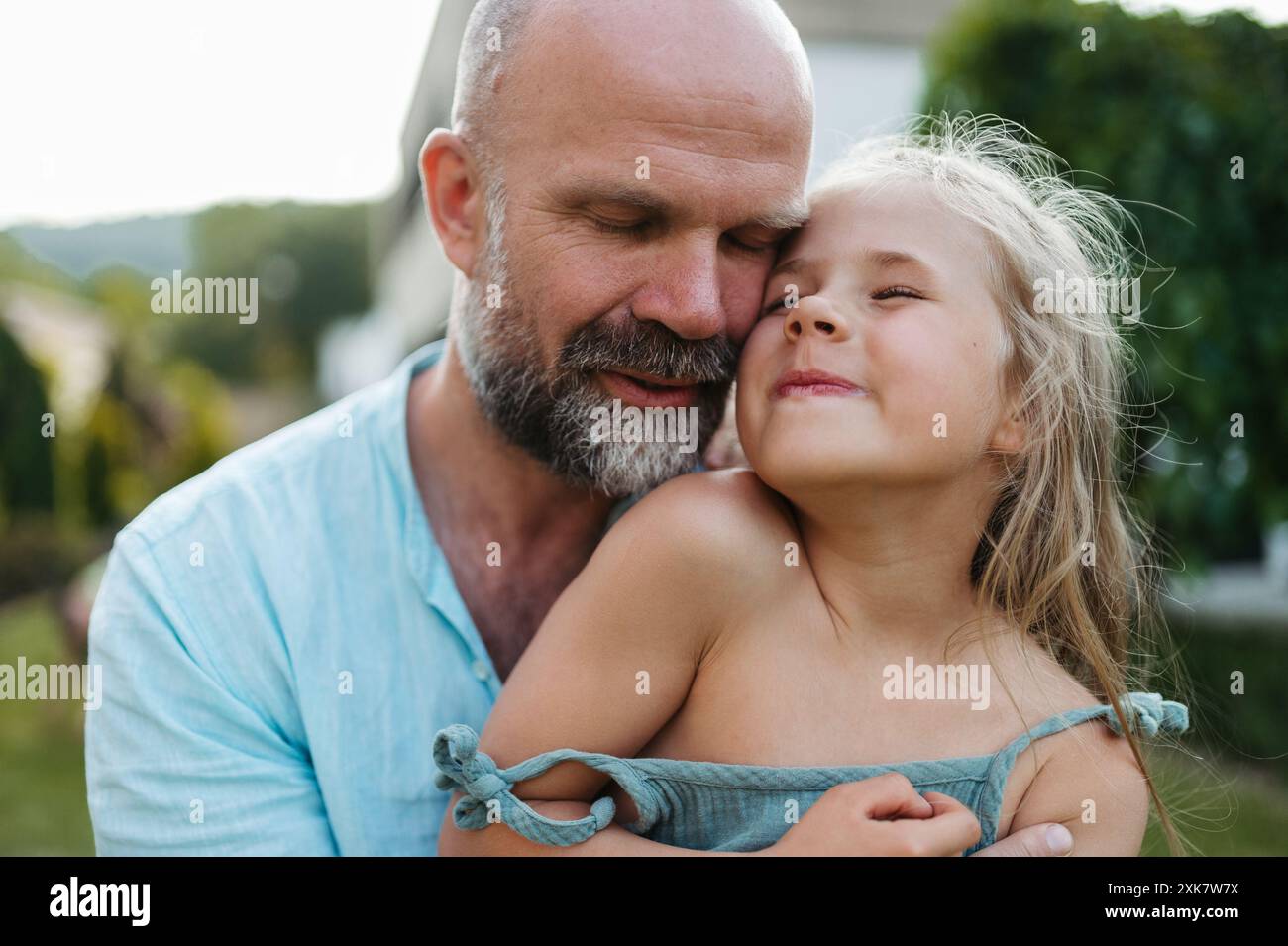 Portrait of father embracing his beautiful daughter in the garden. Dad and daughter spending