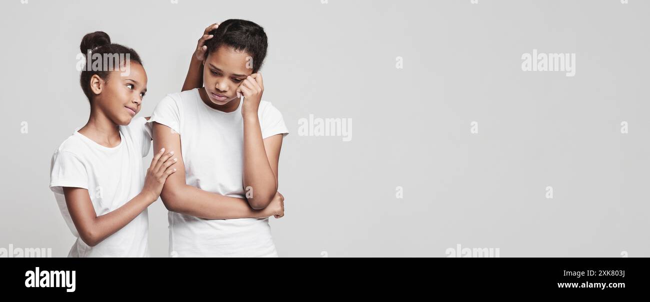 Little girl comforting her girlfriend over grey background Stock Photo ...