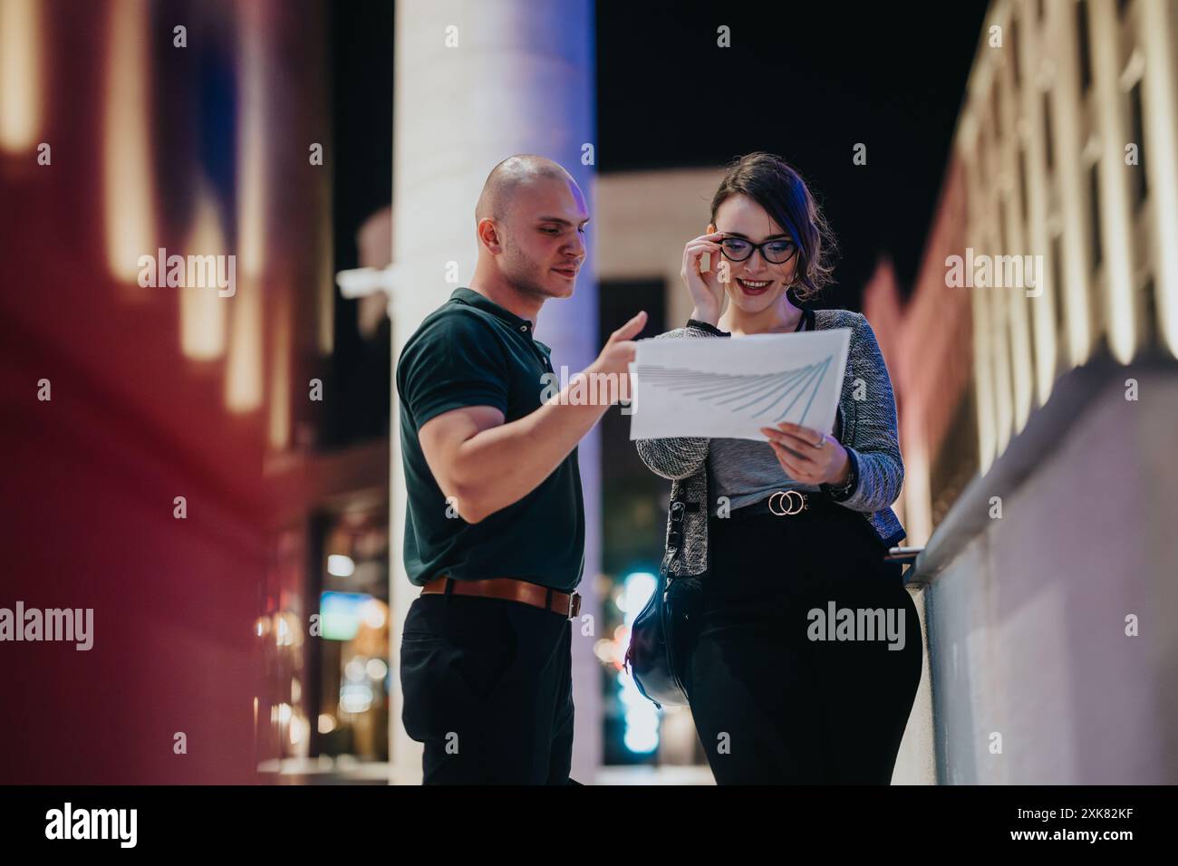 Colleagues discussing business reports at night in urban setting Stock Photo