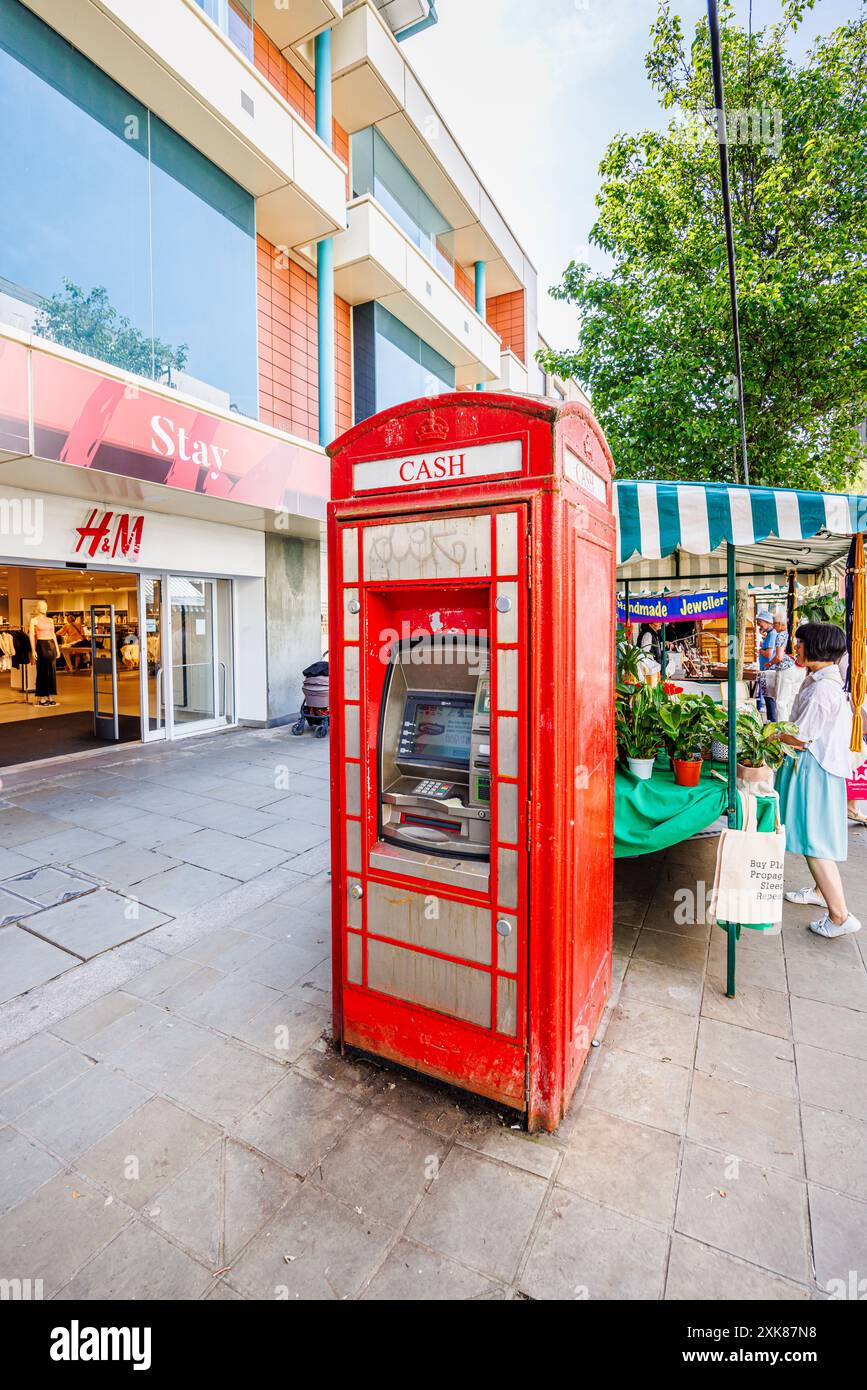 A traditional red telephone box converted into an ATM cash dispenser in a street in Worcester, county town of Worcestershire, West Midlands, England Stock Photo