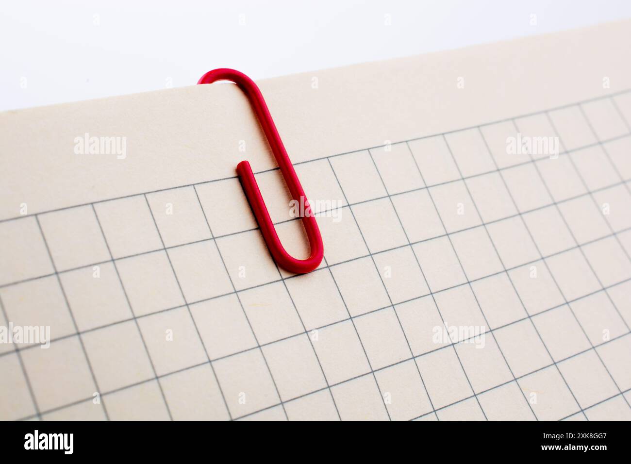 Colored paper clip on a checked notebook  page Stock Photo
