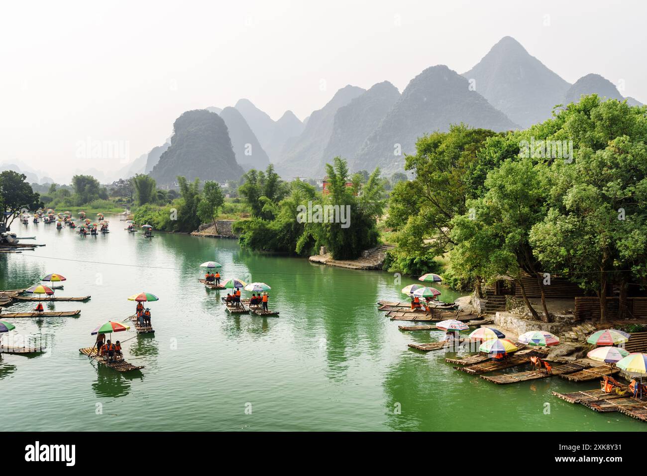 Asian tourists traveling by bamboo rafts along the Yulong River Stock Photo