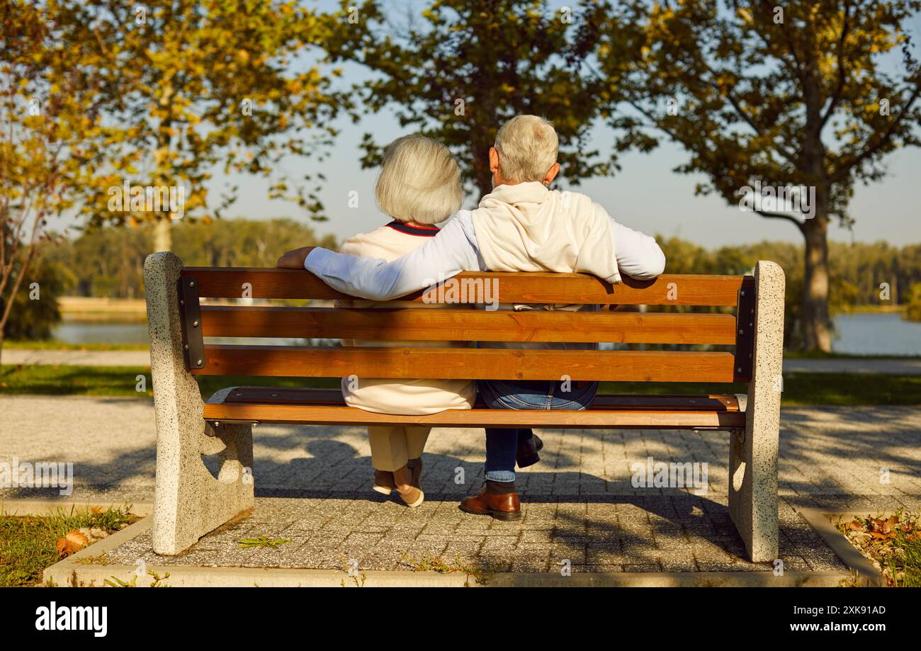 Senior Couple Embracing On Bench In City Park Stock Photo