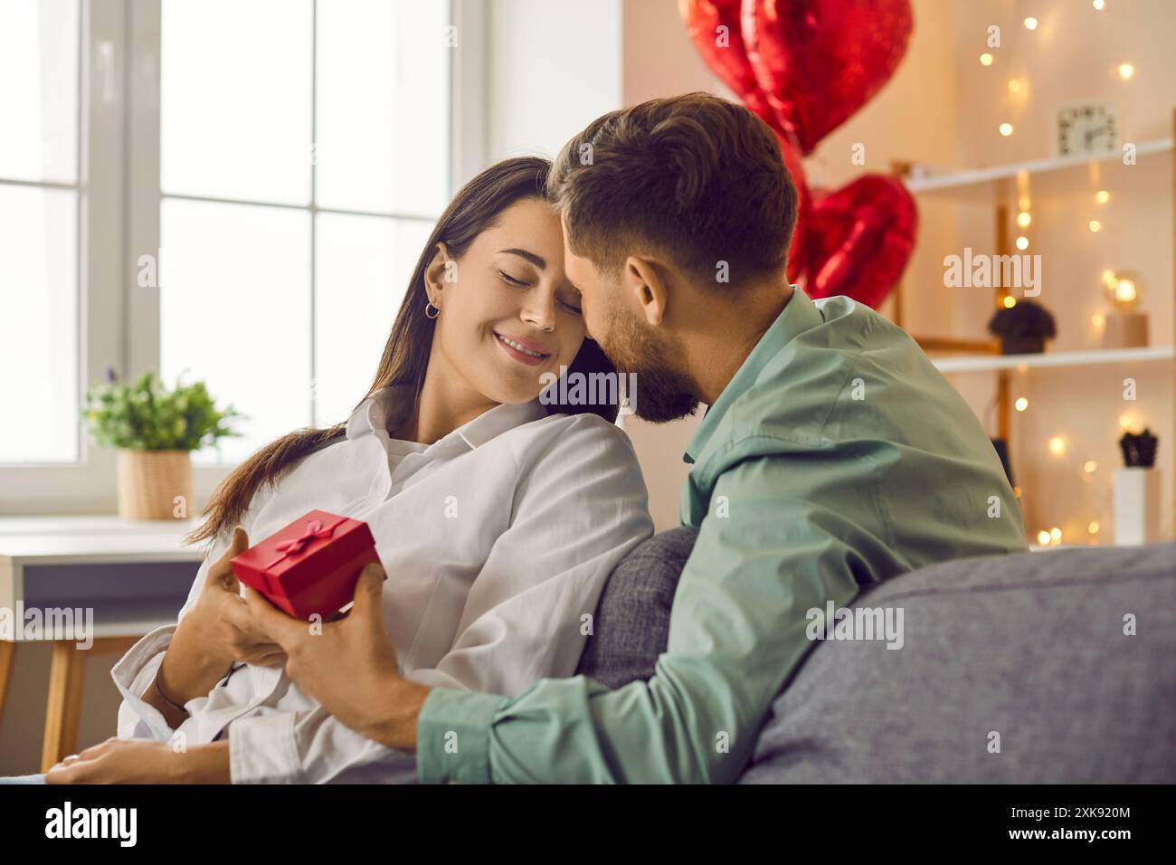 Happy, handsome, young man gives gift to his attractive lover on Valentine's day, birthday, holiday. Couple in love celebrate in a romantic atmosphere Stock Photo