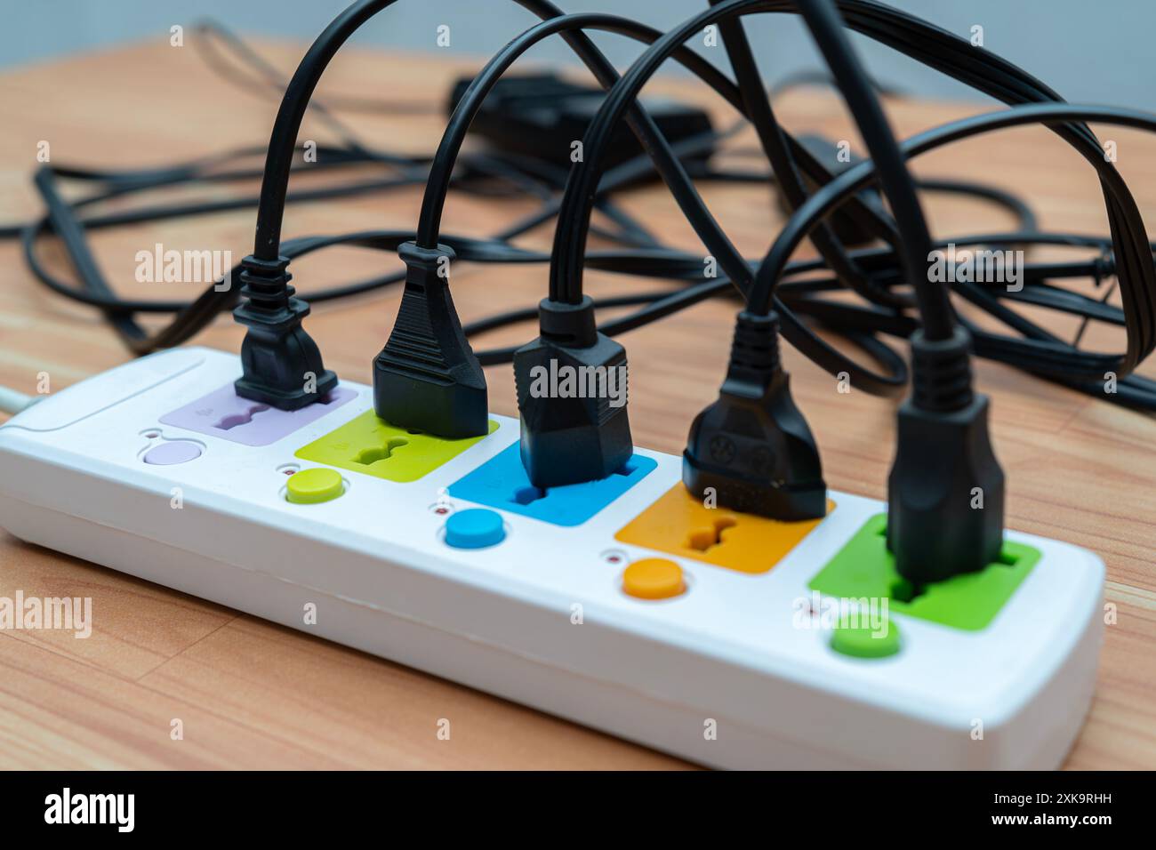 Socket strip and connected plugs on background. Many plugs connected to the power strip with individual switches. Surge protector with connected white Stock Photo
