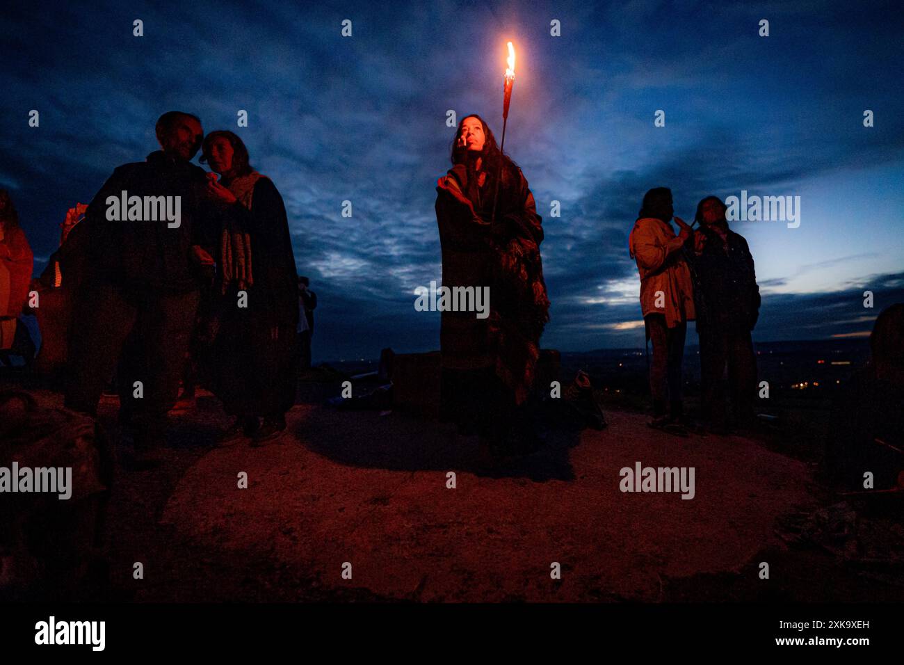 A woman holds a torch and watches the moon rise on the pilgrimage of ...