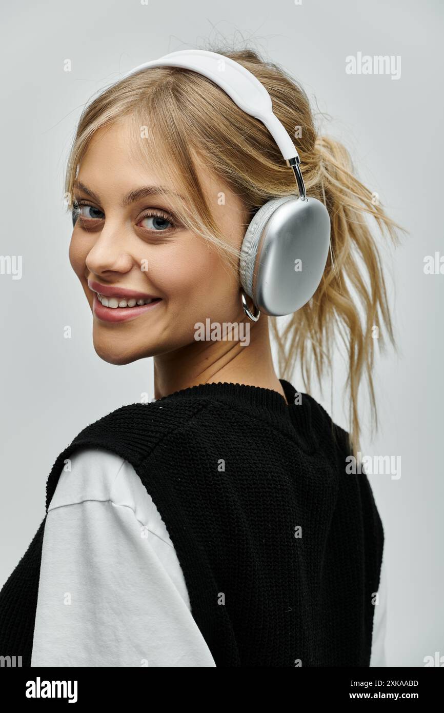 A young woman with blonde hair wearing headphones smiles warmly at the ...