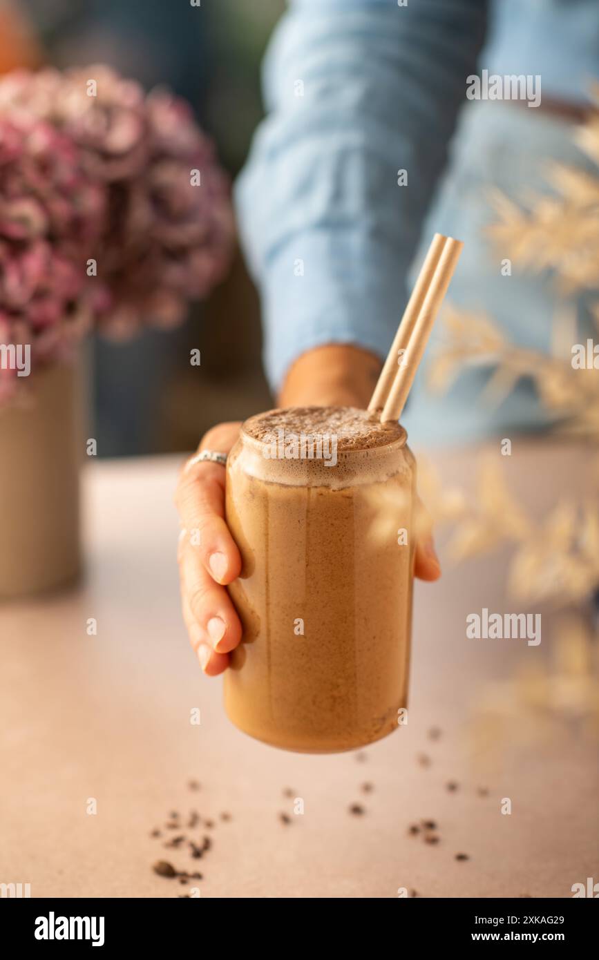 Female holding a glass of vegan chocolate and coffee smoothie in a coffee shop. Brown smoothie. Stock Photo
