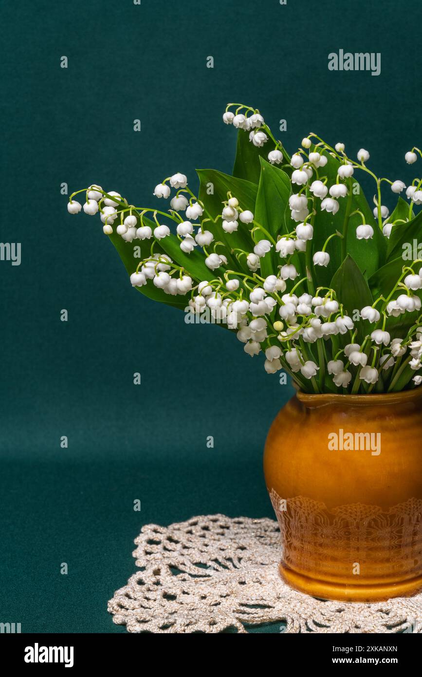 a bouquet of white lilies of the valley in a vase on a green background ...