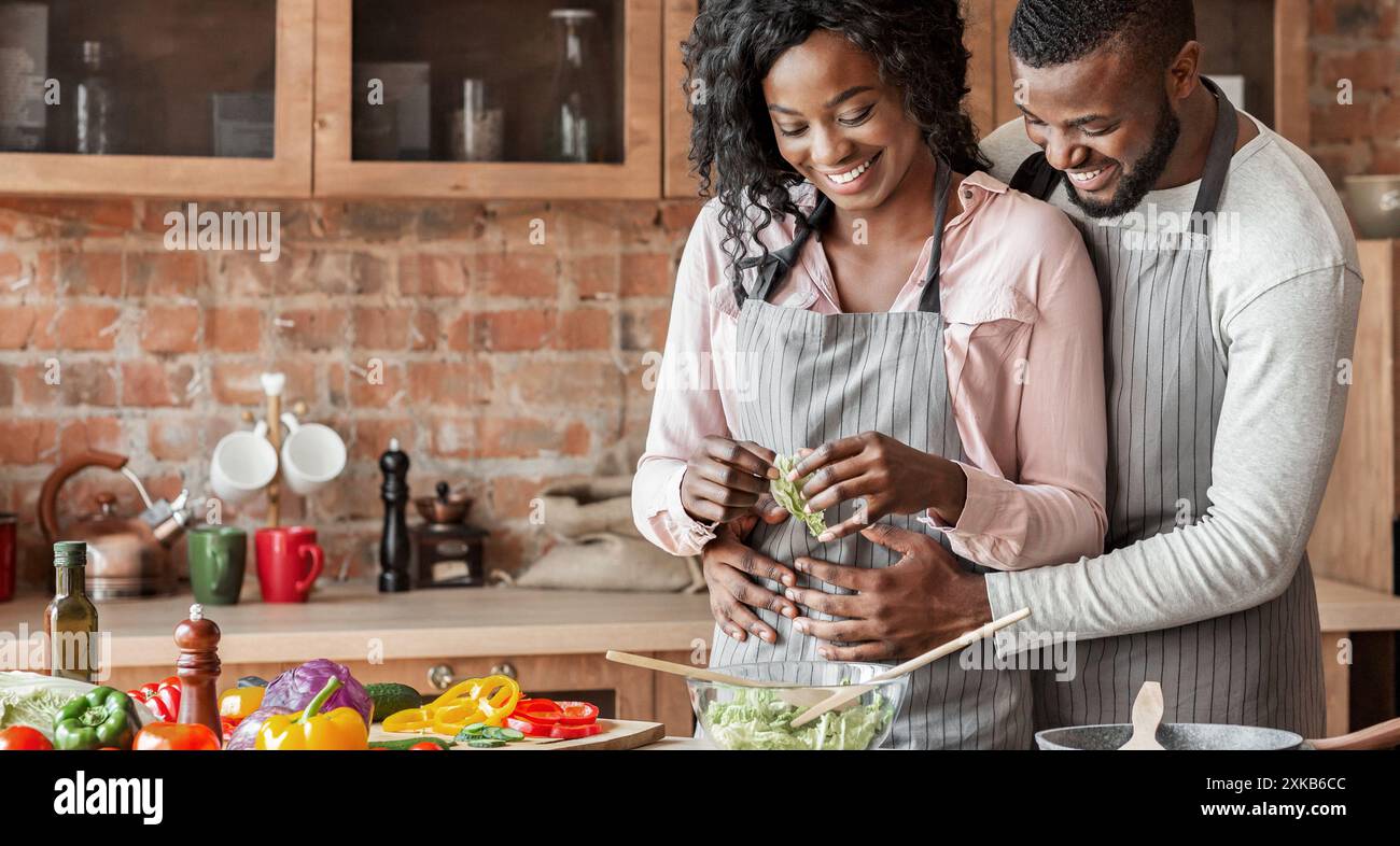 Husband hugging his wife from behind while cooking Stock Photo