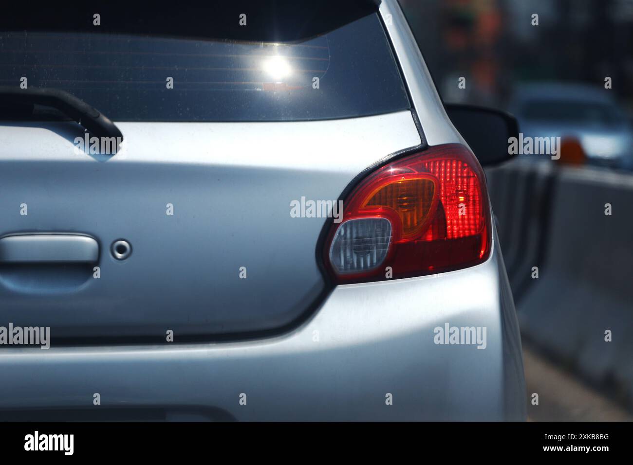 Red lights on the back of a bronze-colored sedan while the engine was turned off and lights reflected on the rear window of the car. Stock Photo