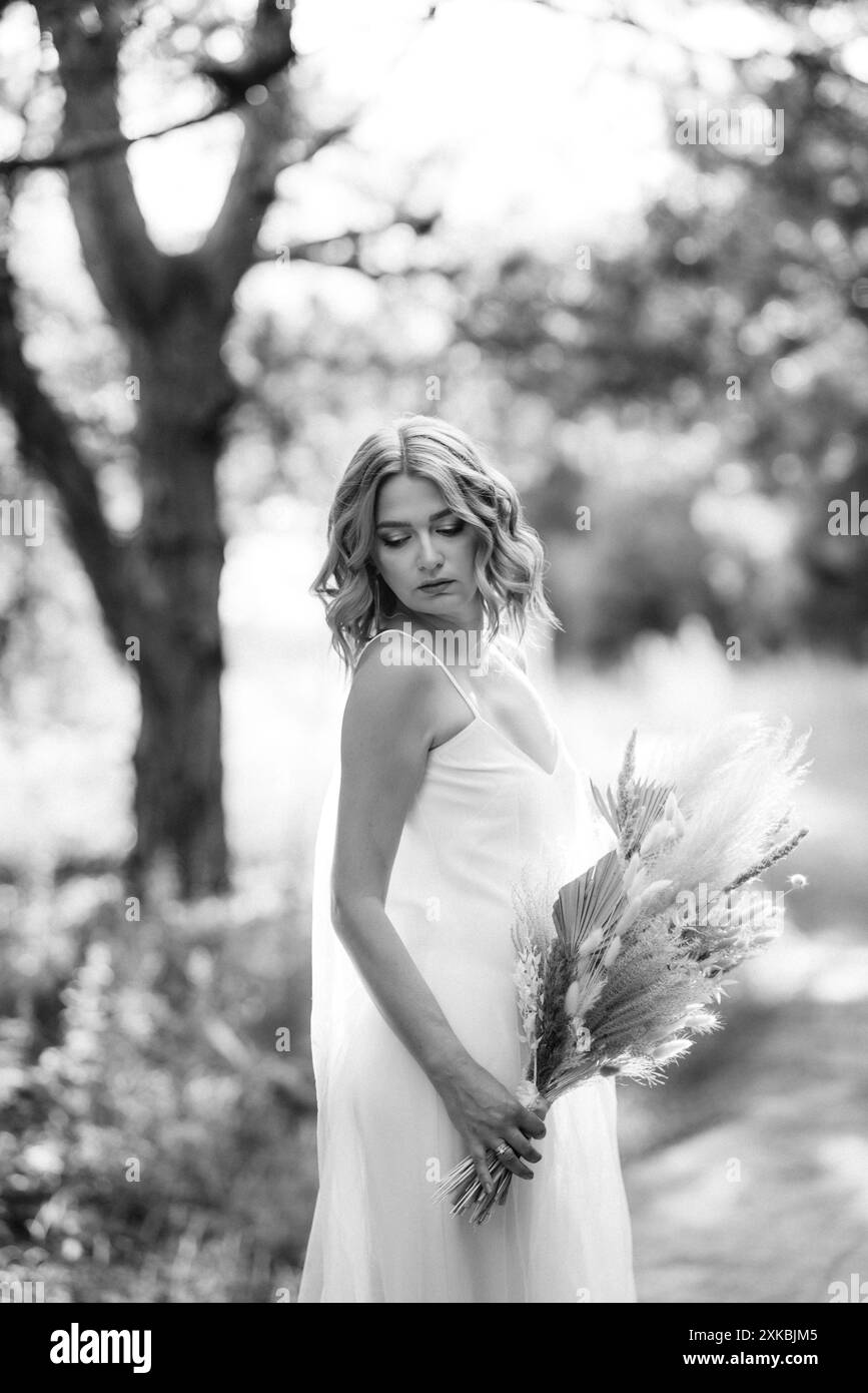 happy bride girl in a white light dress with a bouquet of dried flowers ...