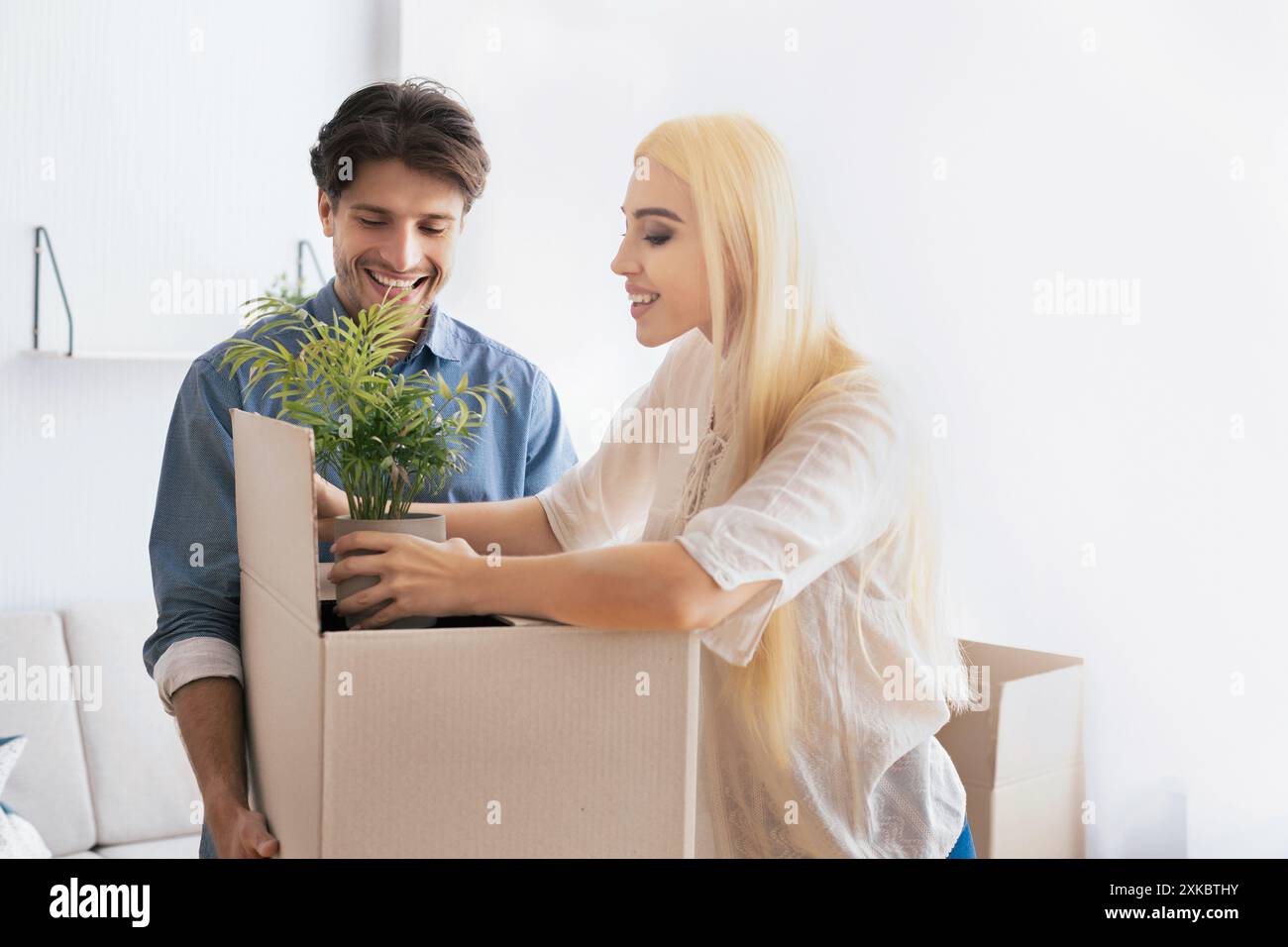 Cheerful Spouses Packing Things In Moving Boxes Preparing For Relocation Stock Photo
