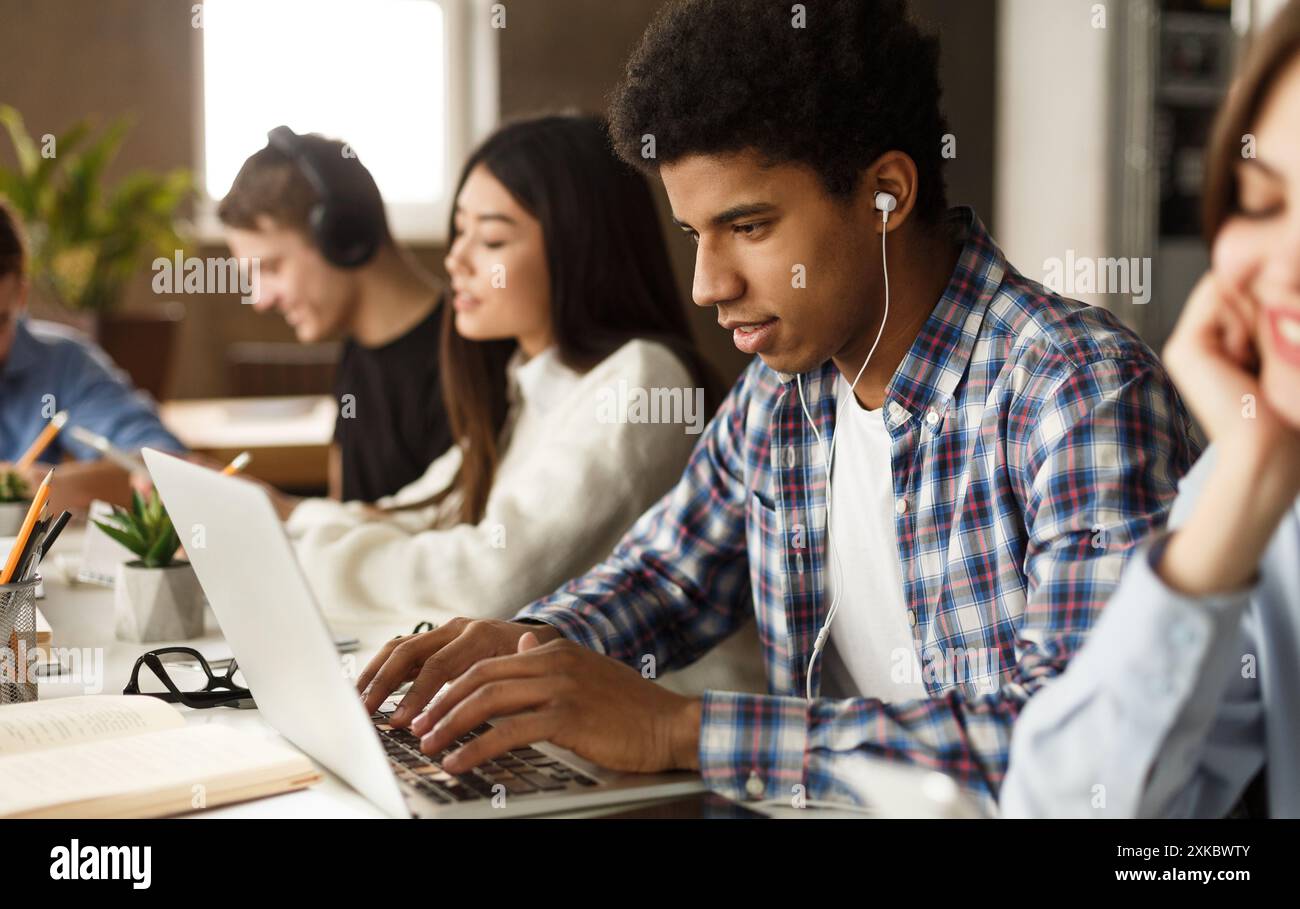 Student learning lessons in school library, using laptop Stock Photo