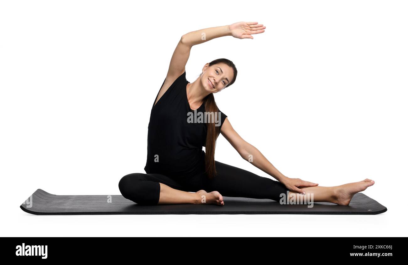 Beautiful pregnant woman doing stretching exercises on mat against ...