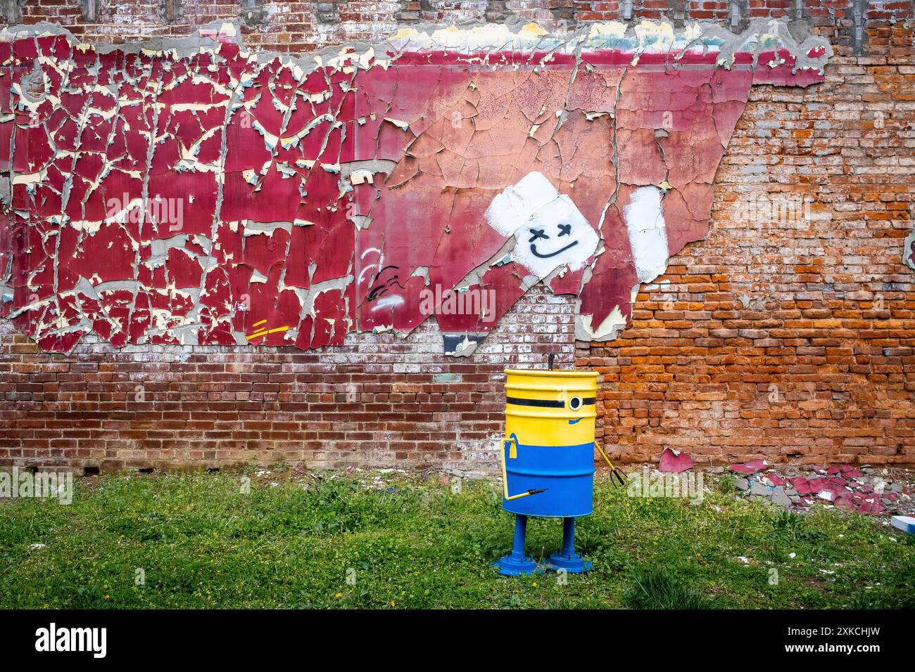 Red paint, smiley face, unique trash can, fading brick wall, recycled material Stock Photo