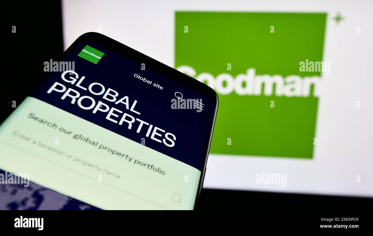 Mobile phone with website of Australian property company Goodman Group in front of business logo. Focus on top-left of phone display. Stock Photo