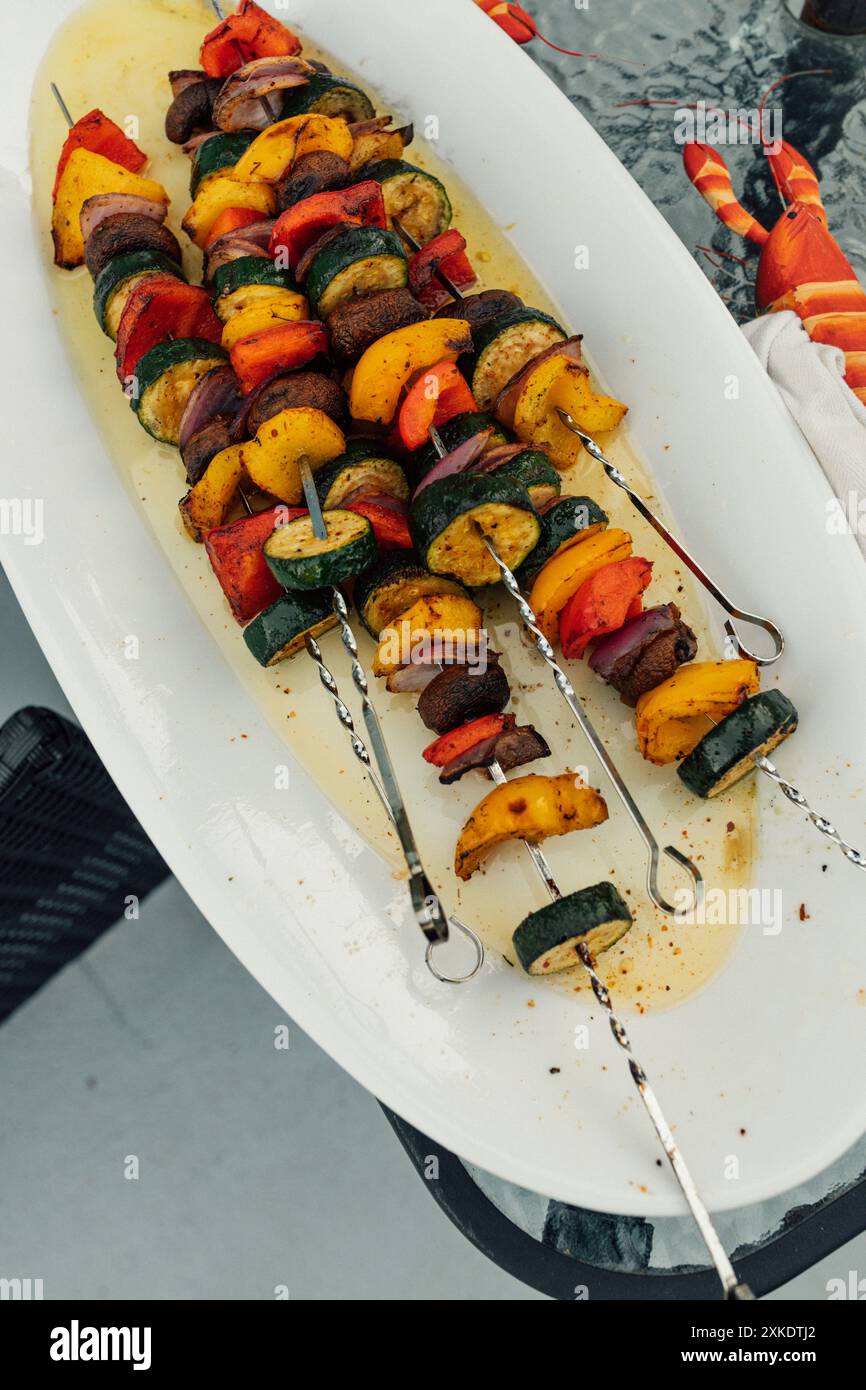 grilled vegetable kabobs, metal skewers on white platter: zucchini, bell pepper, mushroom, red onion Stock Photo