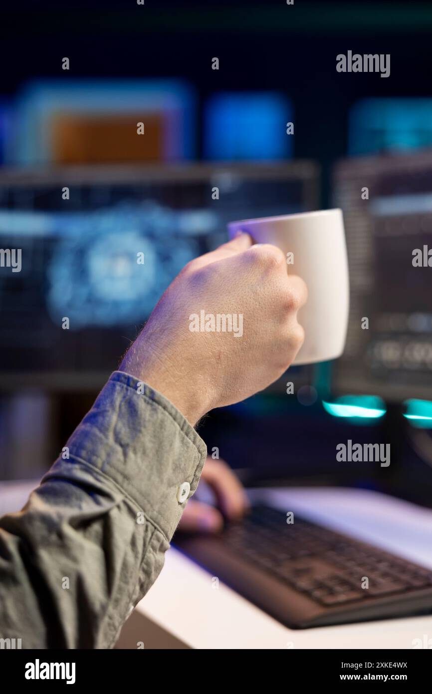 Man drinking coffee and updating artificial intelligence neural networks, writing binary code script. IT professional upgrading high tech AI, enjoying hot beverage, close up Stock Photo