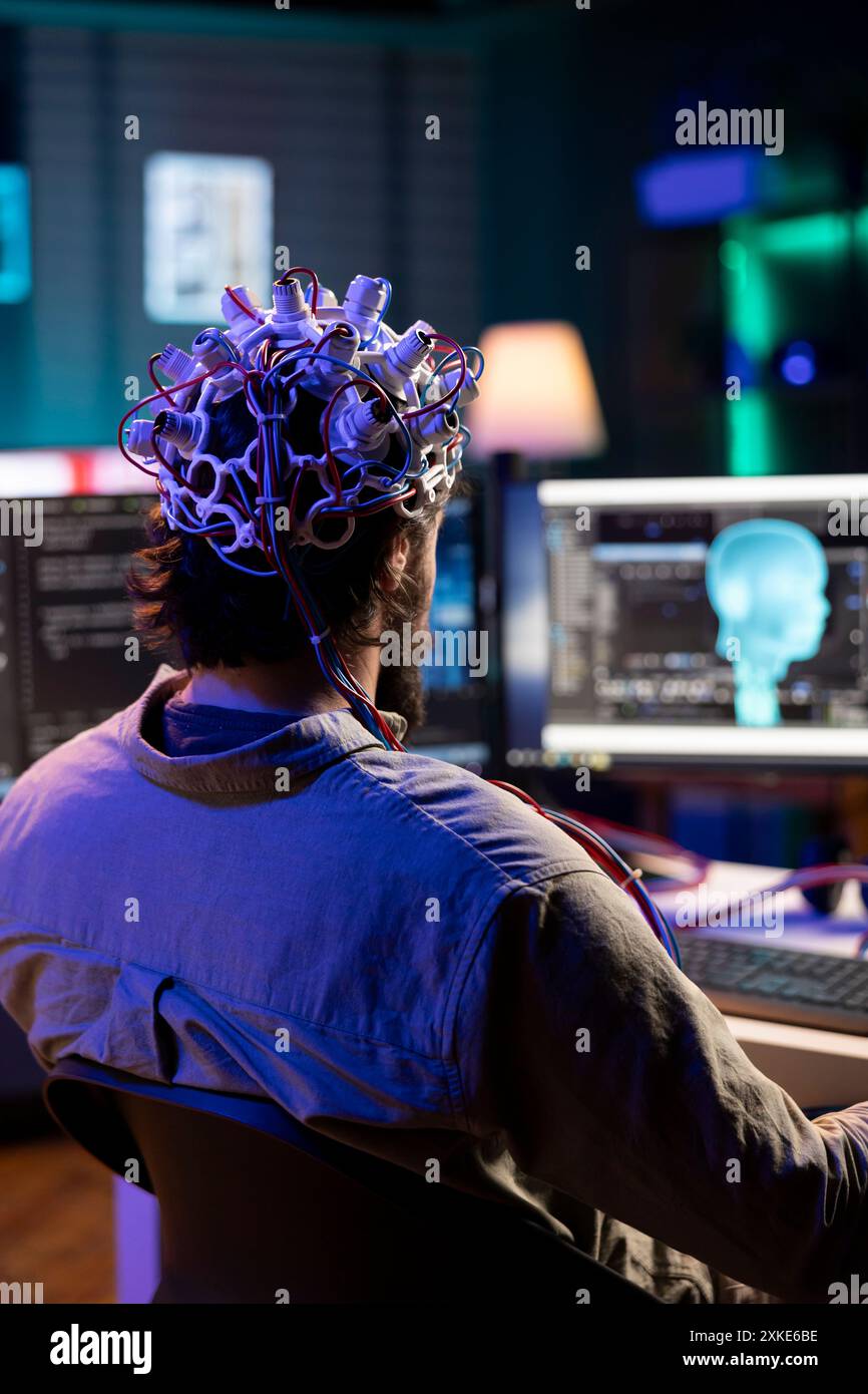 Software engineer using EEG headset translating thoughts into PC commands using brainwave signals. IT admin controlling computer functions using mind, helped by biosensor technology research Stock Photo