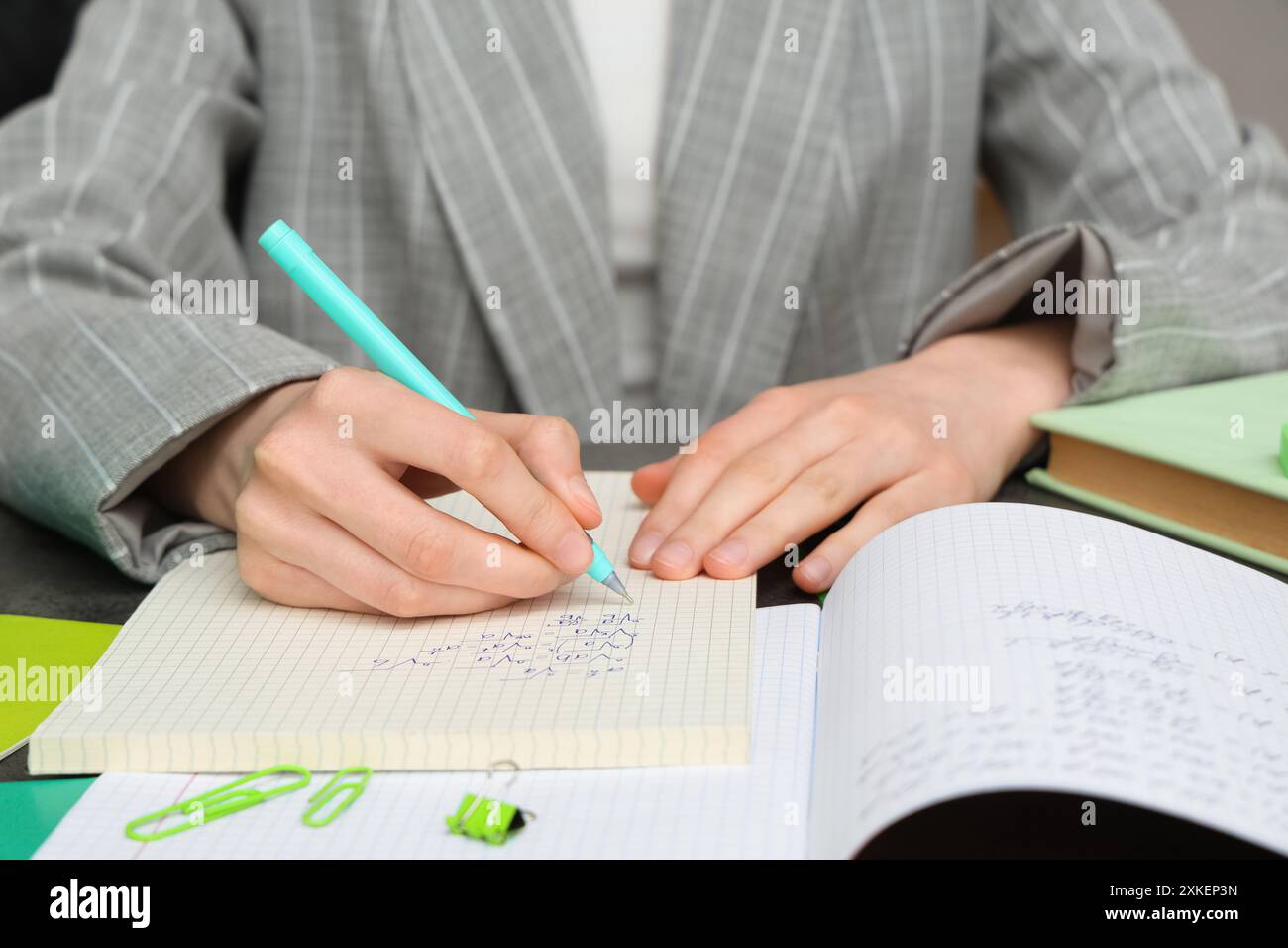 Woman writing math formulas in notebook at table, closeup Stock Photo