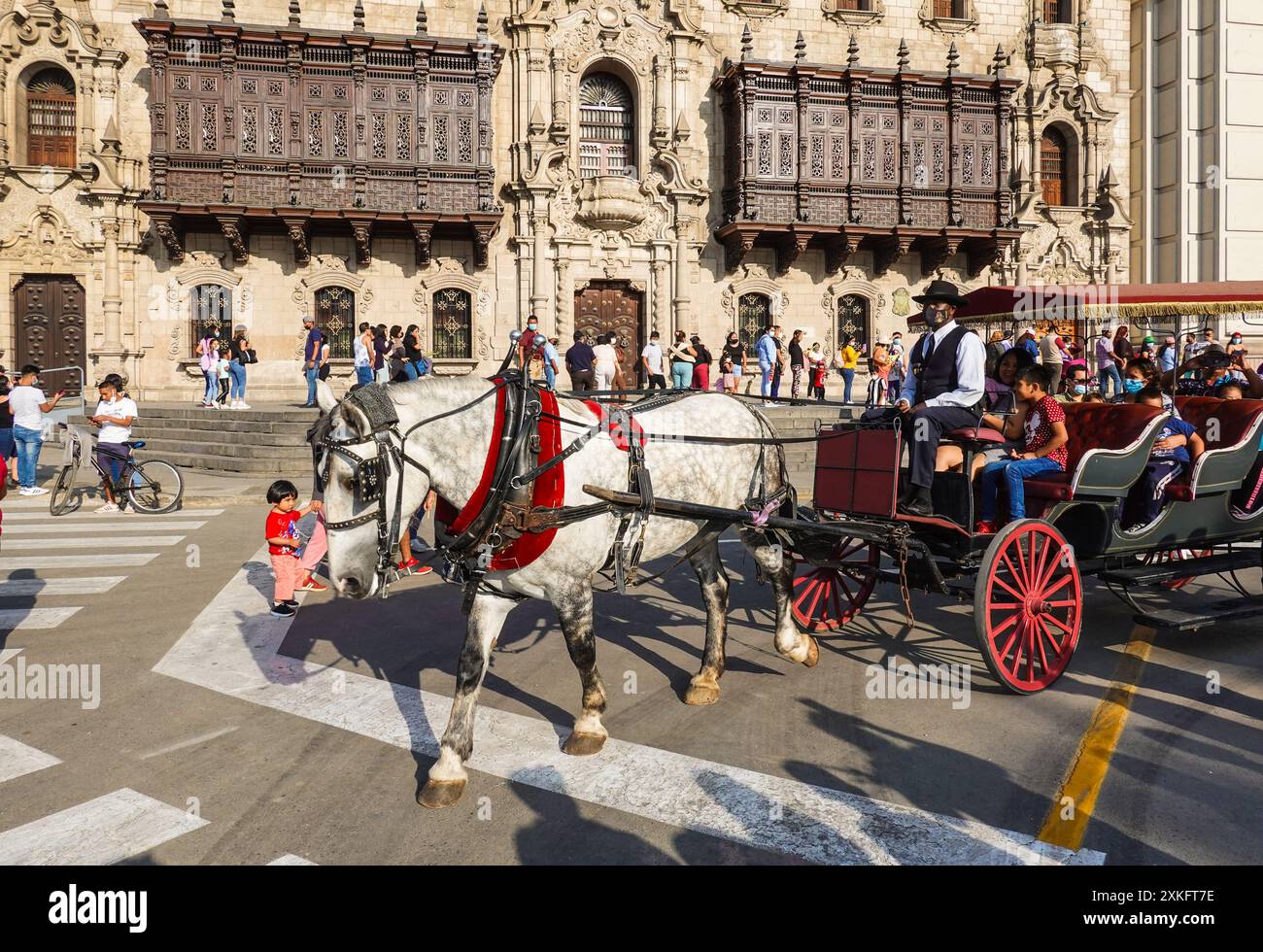 Lima, Peru - April 16 2022: A horse carriage passes the colonial time Archibishop’s Palace and Lima Cathedral in the Plaza Mayor in Peru capital city Stock Photo