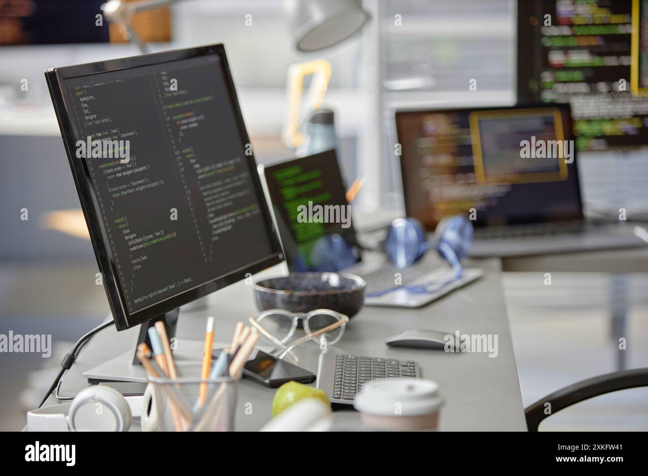 Background shot of software engineer working desk with multiple computer screens displaying programming code in IT office, copy space Stock Photo