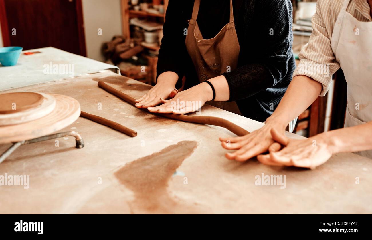 Pottery, people and hands on clay for roll, teaching and design process in workshop. Sculptor, coaching and rope of mud on table for production Stock Photo