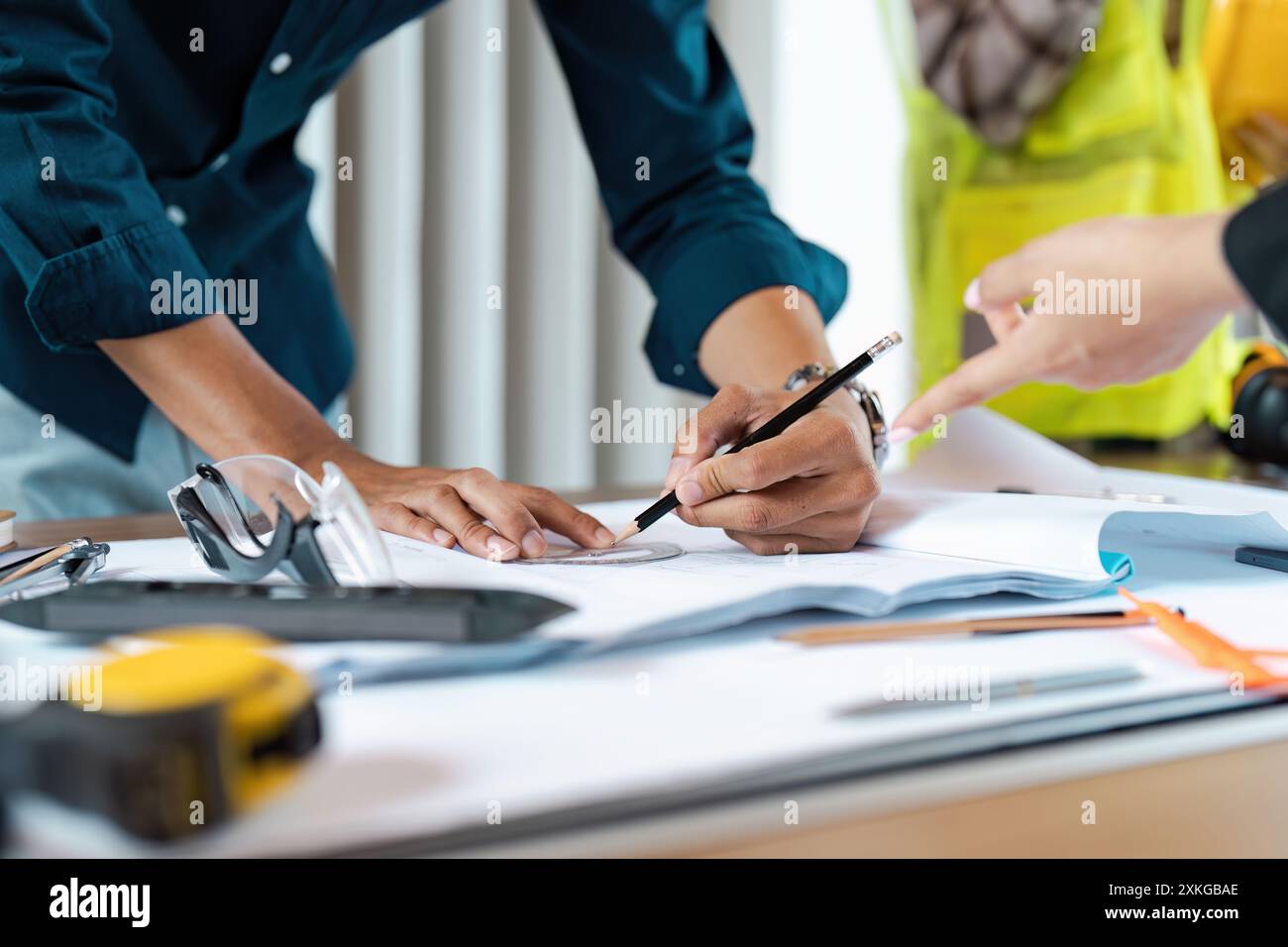 Engineer Working on Blueprint with Colleague in Modern Office Setting ...