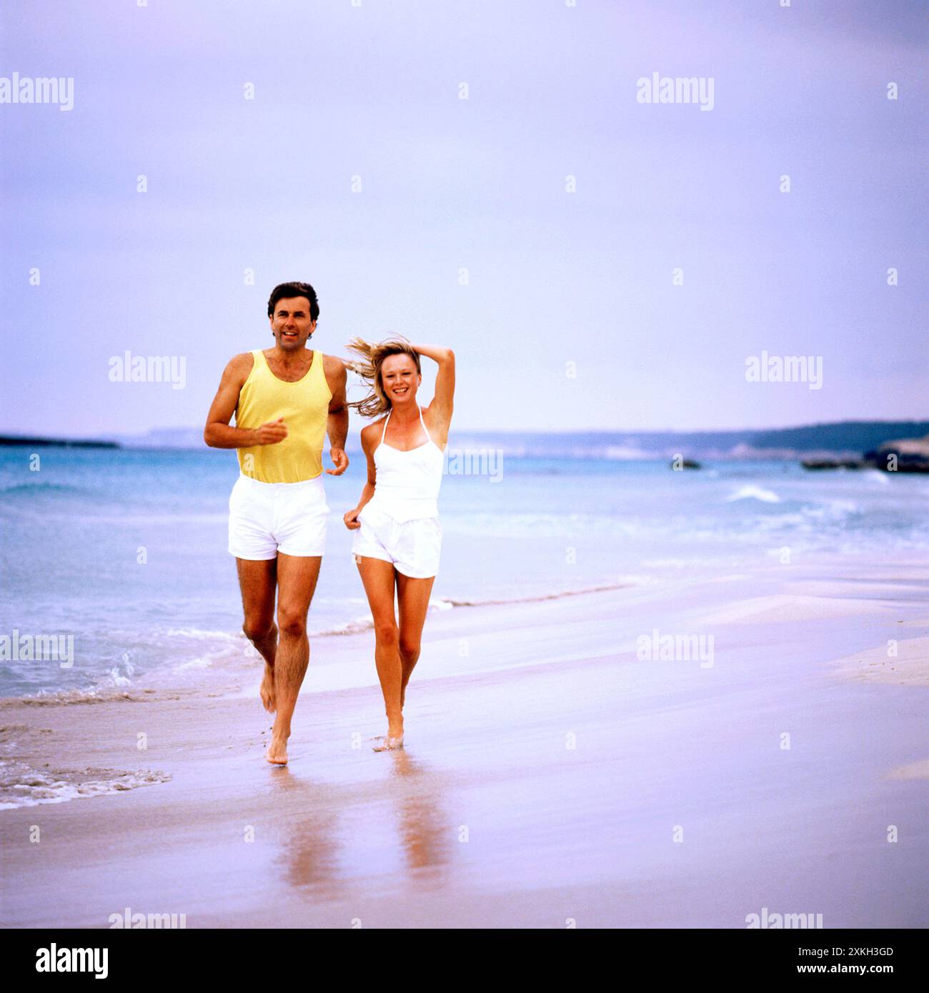 Young couple jogging on a beach. Stock Photo