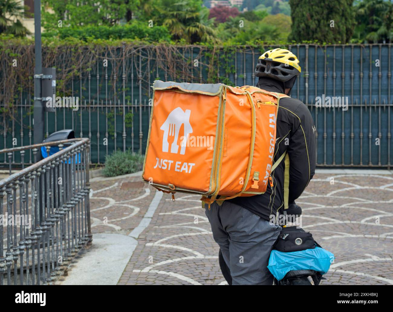 Just Eat courier holding bike, Como, Italy Stock Photo