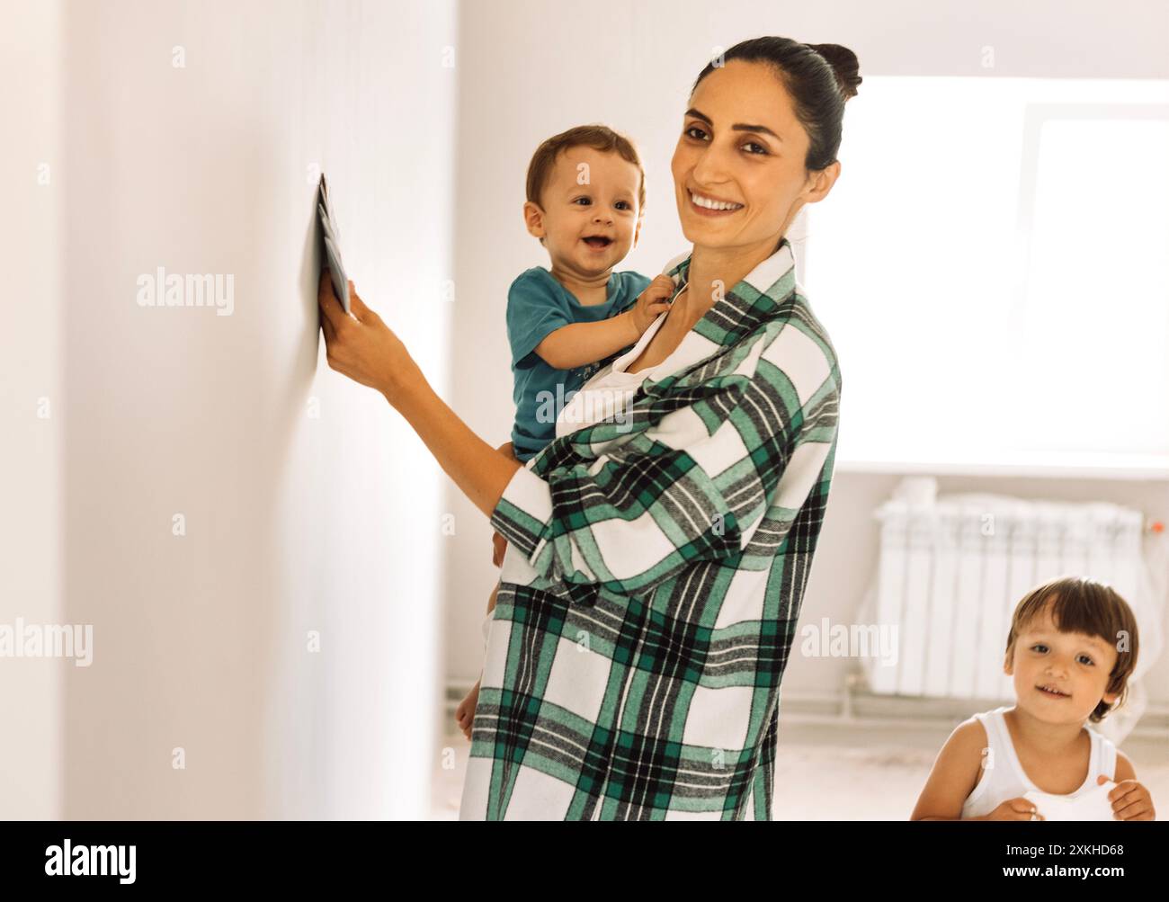 Woman with children in casual clothes chooses color to paint walls in ...