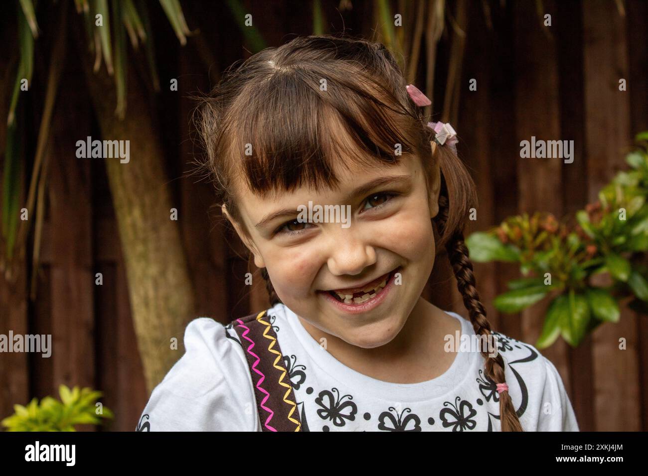 little child girl smiling and posing in front of tree Stock Photo - Alamy
